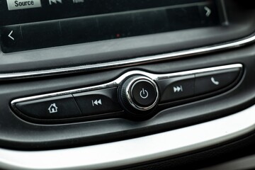 Power button and various controls of a car radio in an interior of modern vehicle