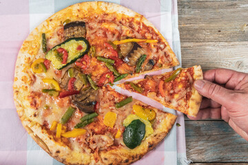 Tasty grilled vegetable pizza cooked with ingredients on wooden background.