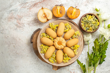 a plate of cookies on wooden platter and a bowl of herbs and half-pear and palm and flowers