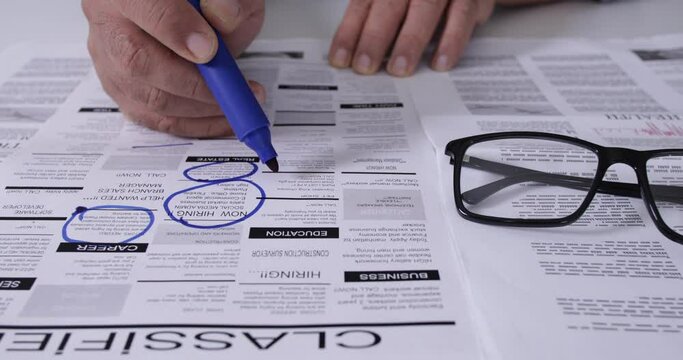 man looking for a new job in newspaper classified