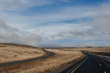 A beautiful landscape with a highway along which cars and trucks drive, on a sunny autumn day among the mountains, a blue sky with fluffy gray-blue clouds. Oregon, USA, 12-5-2019