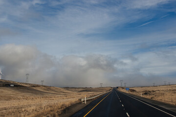 Fototapeta premium A beautiful landscape with a highway along which cars and trucks drive, on a sunny autumn day among the mountains, a blue sky with fluffy gray-blue clouds. Oregon, USA, 12-5-2019