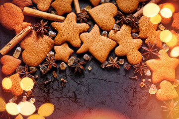 Christmas gingerbread cookies in various shapes and twinkling lights on a dark background. Festive background with copy space