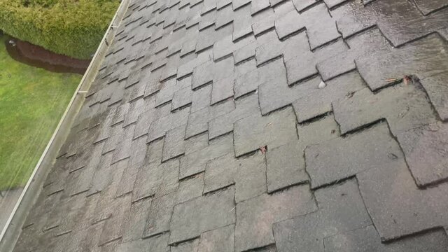 Rain water flowing from home roof into gutter during rain storm in 4K format 