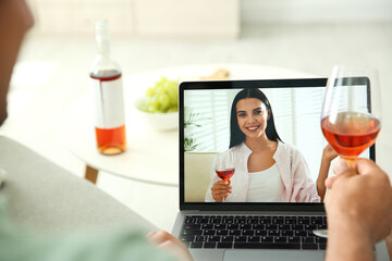 Friends drinking wine while communicating through online video conference at home. Social distancing during coronavirus pandemic