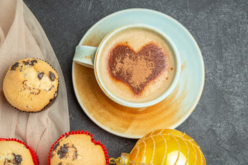 Close up view of delicious freshly baked small cupcakes and a cup of frothy coffee on towel accessory on black background