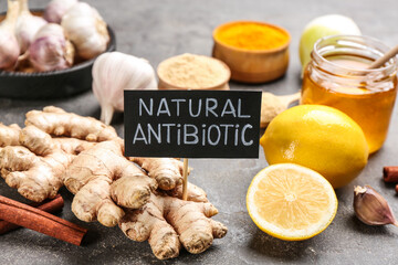 Different fresh products and card with phrase Natural Antibiotic on grey table