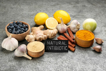 Different fresh products and card with phrase Natural Antibiotic on grey table