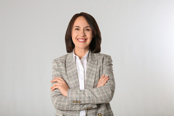 Portrait of mature businesswoman on light grey background - Powered by Adobe