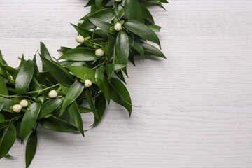 Beautiful handmade mistletoe wreath on white wooden table. Space for text