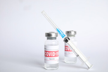 Vials with coronavirus vaccine and syringe on white background