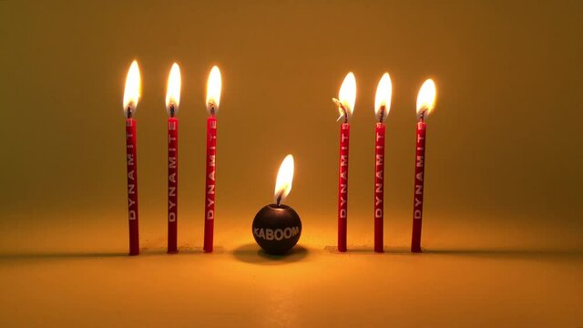 Funny birthday candles reading dynamite burning on a yellow background 