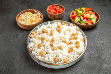 Horizontal view of seasoned split peas and rice for dinner and sauerkraut and salad on dark table