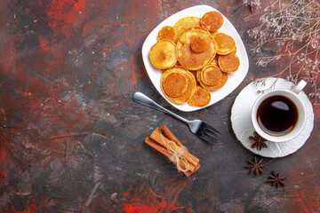 Overhead view of homemade pancakes a cup of tea fork and cinnamon