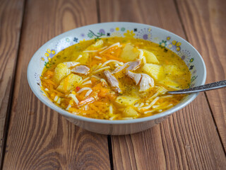 Soup with chicken drumstick and pasta in a deep light plate