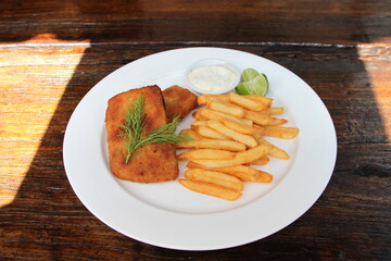Crumbed Barramundi fish fillet served with French fries, sauce tartar and lime