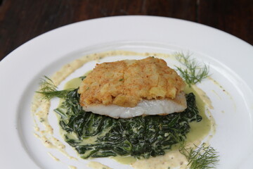 Barramundi fish fillet with potato mustard on sauteed spinach and mustard cream sauce