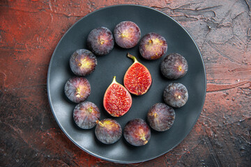 Above view of full fresh black mission figs split ones on a black plate on colorful background