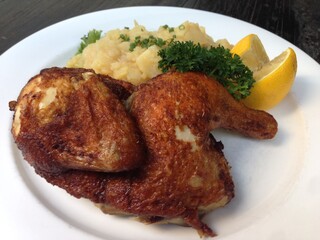 Grilled half chicken served with potato salad and lemon