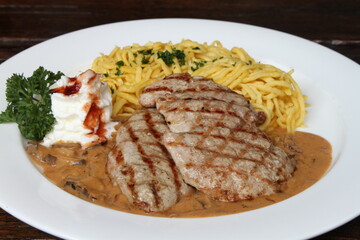 Pork escalope hunter style in creamy sauce served with spaetzle and whipped cream
