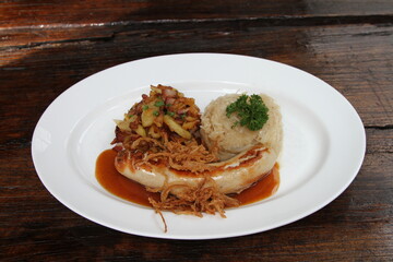 Veal sausage with crispy onions on gravy, served with sauerkraut and fried potatoes