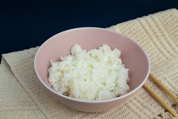 Pink bowl of cooked rice with bamboo hashi