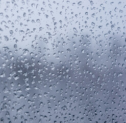 Melting snow on the glass, drops of water condensation on the window, and transparent glass of the window in cold winter, winter landscape outside the window, close-up.