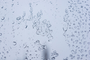 Melting snow on the glass, drops of water condensation on the window, and transparent glass of the window in cold winter, winter landscape outside the window, close-up.