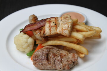 Mixed grill with beef and pork steak, Nuremberg sausage, crispy bacon, butter vegetables, French fries and dip