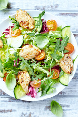 Salad with Chicken Breast, Cherry Tomatoes, Cucumber, Rocket and fresh Basil. Bright wooden background. Top view. Close up. 