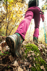 Hiking girl in a mountain. Low angle view of generic sports shoe and legs in a forest. Healthy fitness lifestyle outdoors.