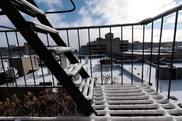 rooftop cityscape right after a snowstorm taken from a snow covered fire escape with bright clouds...