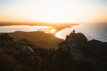 Man sitting and watching the sun rise from the top of east mount barren in the Fitzgerald river national park. 