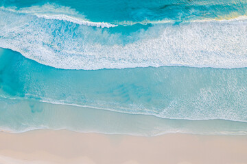 Fototapeta na wymiar top down view of waves crashing against an empty beach. 