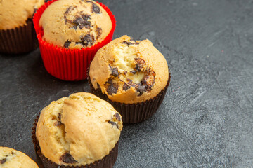 Half shot of freshly baked small cupcakes with chocolates on dark table