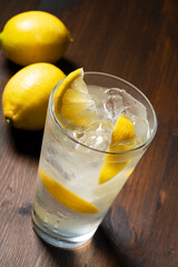 A lemon sour in a glass set against a dark wooden background