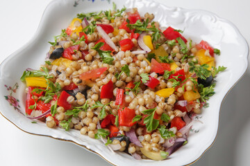 Wheat salad in a bowl. Wheat, peppers, tomatoes, olives, lemon, parsley, olive oil and salt