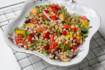 Wheat salad in a bowl. Wheat, peppers, tomatoes, olives, lemon, parsley, olive oil and salt