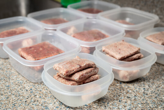 Raw Food Diet Meal Prep For Cats; Dogs Or Pets. Frozen Raw Ground Chicken And Turkey Meat Inclusive Backs; Necks; Liver And Hearts Separated In Daily Tupperware Portions For Two Cats. Selective Focus.