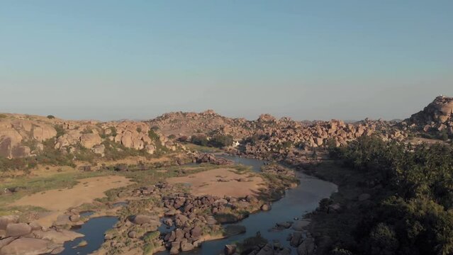 Granite outcrops and rocky landscape alongside the Tungabhadra River in Hampi, Karnataka, India - Aerial ascending wide shot