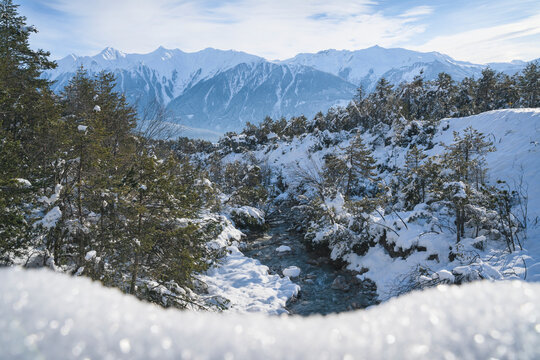Sunny winter landscape with mountain river in deep snow and evergreen trees in Austrian Alps, Mieming, Tyrol, Austria