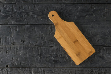 A small cutting Board on a black wooden table.