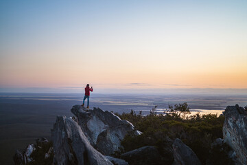 Lone man standing on the top of East Mount Barren as the sun rises behind him. Located in the Fitzgerald River National Park in Hopetoun, Western Australia. 