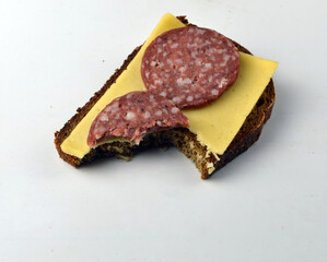 
fresh bitten sandwich with salami lies on the table