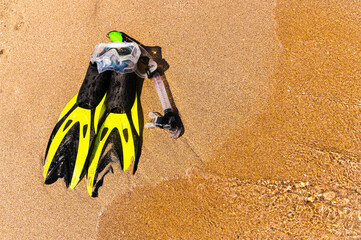 Snorkeling equipment set snorkel mask fins lie on golden sand by the seashore
