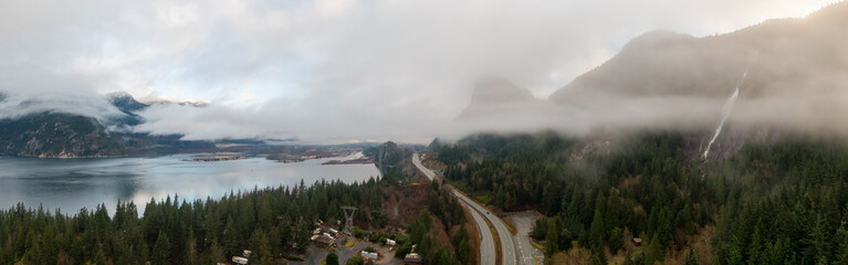 Aerial Panoramic view of Sea to Sky Highway with Chief Mountain in the background during a cloudy winter sunrise. Taken near Squamish, North of Vancouver, British Columbia, Canada.