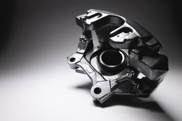 Brake caliper in black. A spare part for a car brake system on a gray background in high contrast.
