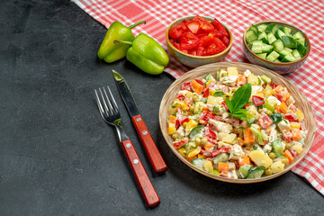 side close view of veggie salad with vegetables and cutleries on side and red napkin under it and place for your text on grey table