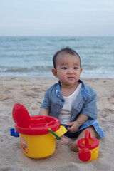 Fototapeta na wymiar Adorable Cute Asian baby boy playing with beach toys on tropical beach