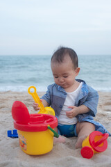 Adorable Cute Asian baby boy playing with beach toys on tropical beach